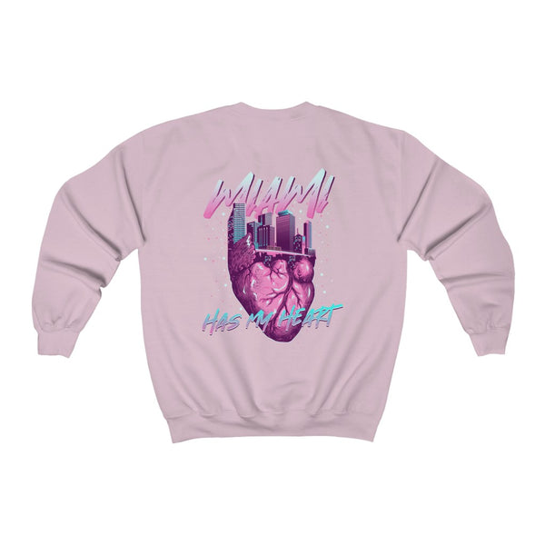 Esta sudadera para mujer presenta un diseño único inspirado en el vibrante horizonte de Miami, con una ingeniosa forma de corazón. La frase "Miami has my Heart" (Miami tiene mi corazón) se destaca, representando el espíritu de la ciudad. La paleta de colores utiliza el azul celeste y el rosa fucsia de Miami Vice, dándole un toque divertido y moderno que captura la esencia del animado ambiente de Miami. ¡Es la prenda perfecta para quienes desean mostrar su amor por esta icónica ciudad!